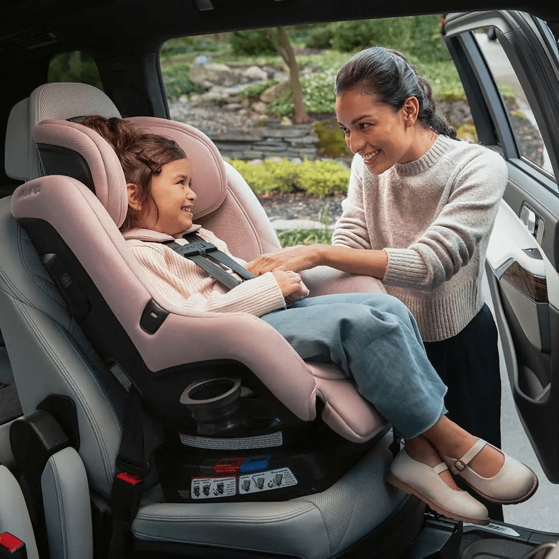 Mother putting baby in a Nuna Rava car seat in Thistle color