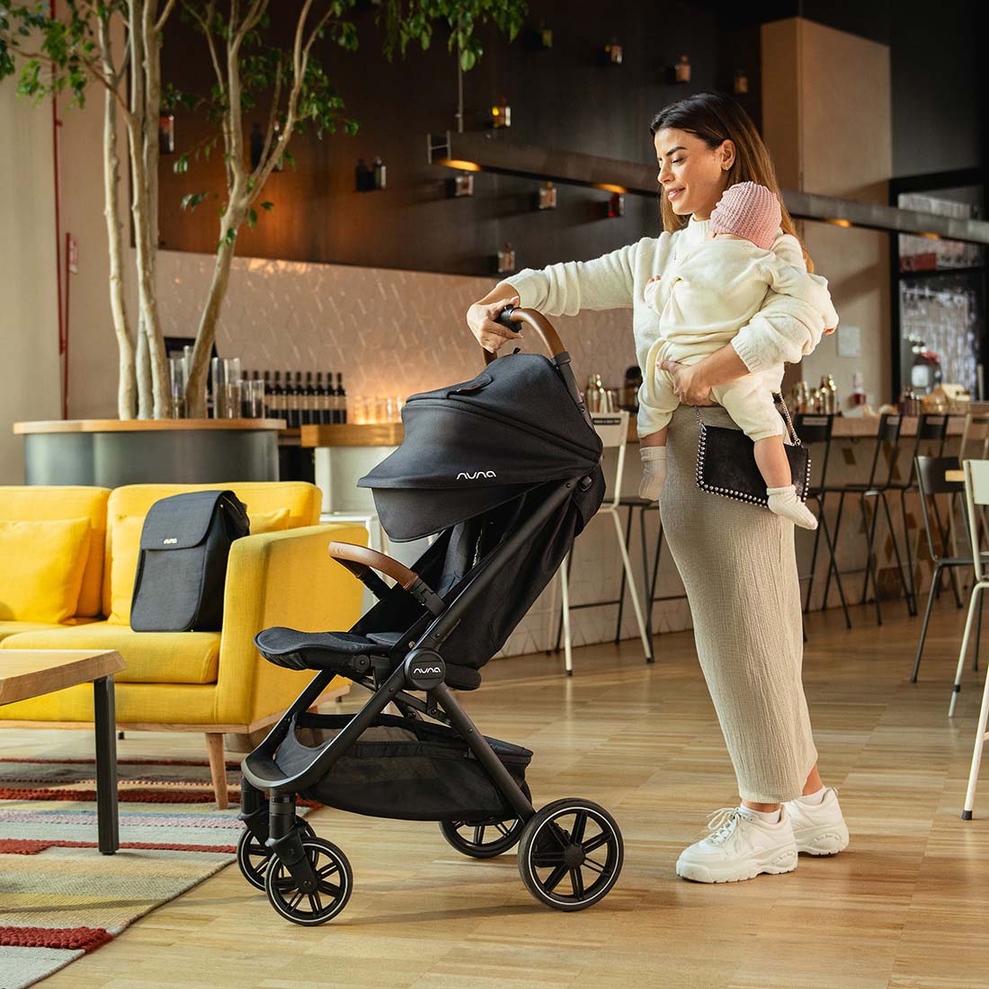 Mother folding Nuna Trvl Lx in Caviar with Chocolate Handle Bar