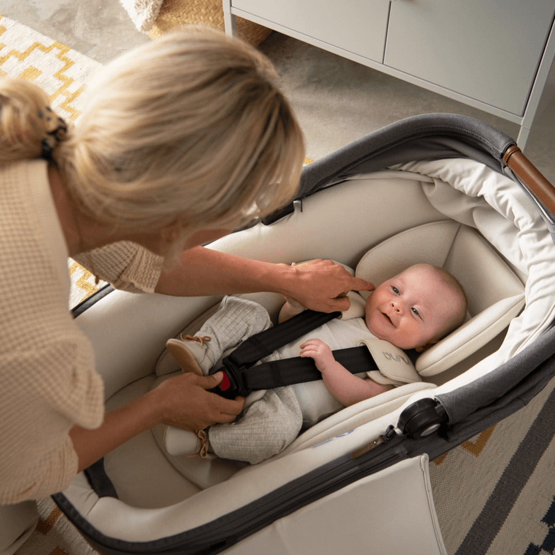 Nuna Cari Next car seat capsule in caviar with happy baby