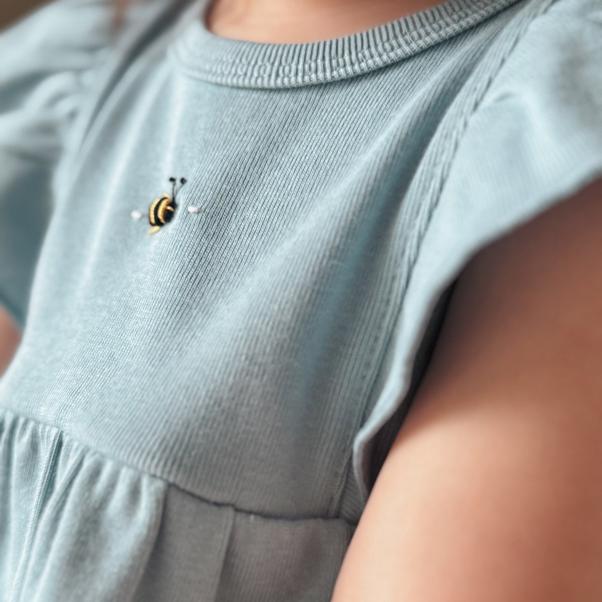 Baby girl wearing Cotton frill dress in ocean and bee embroidery clos up