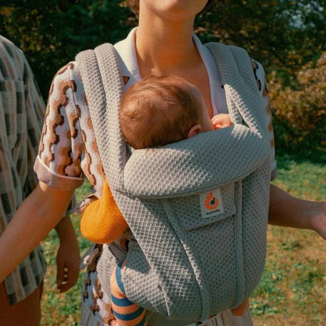 Front view Mother carrying baby in mesh breathable baby carrier