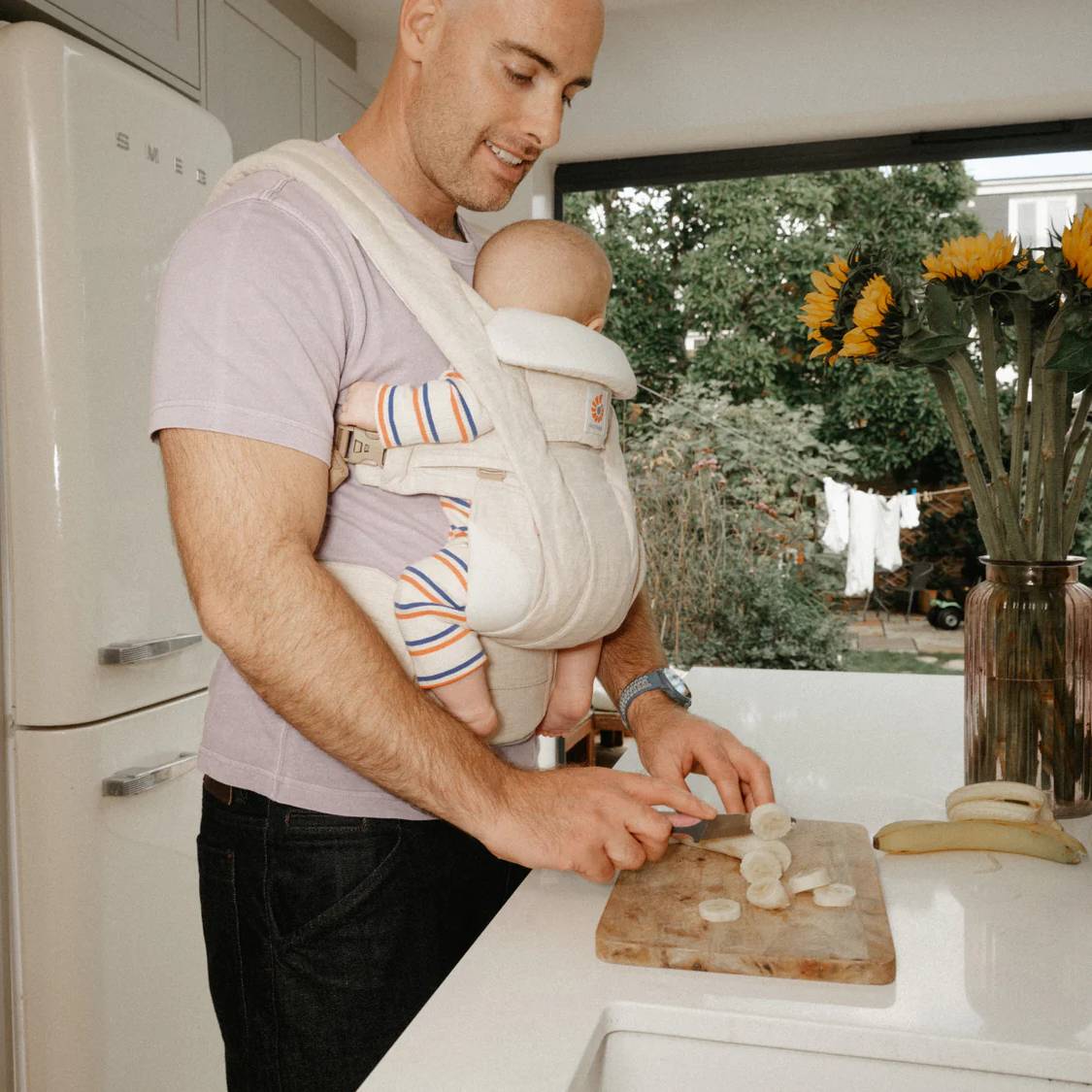 Father in kitchen carrying baby in linen baby carrier