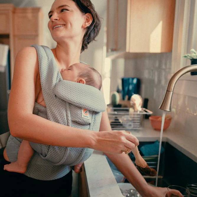 Mother working in kitchen carrying baby in Omni Deluxe Baby Carrier