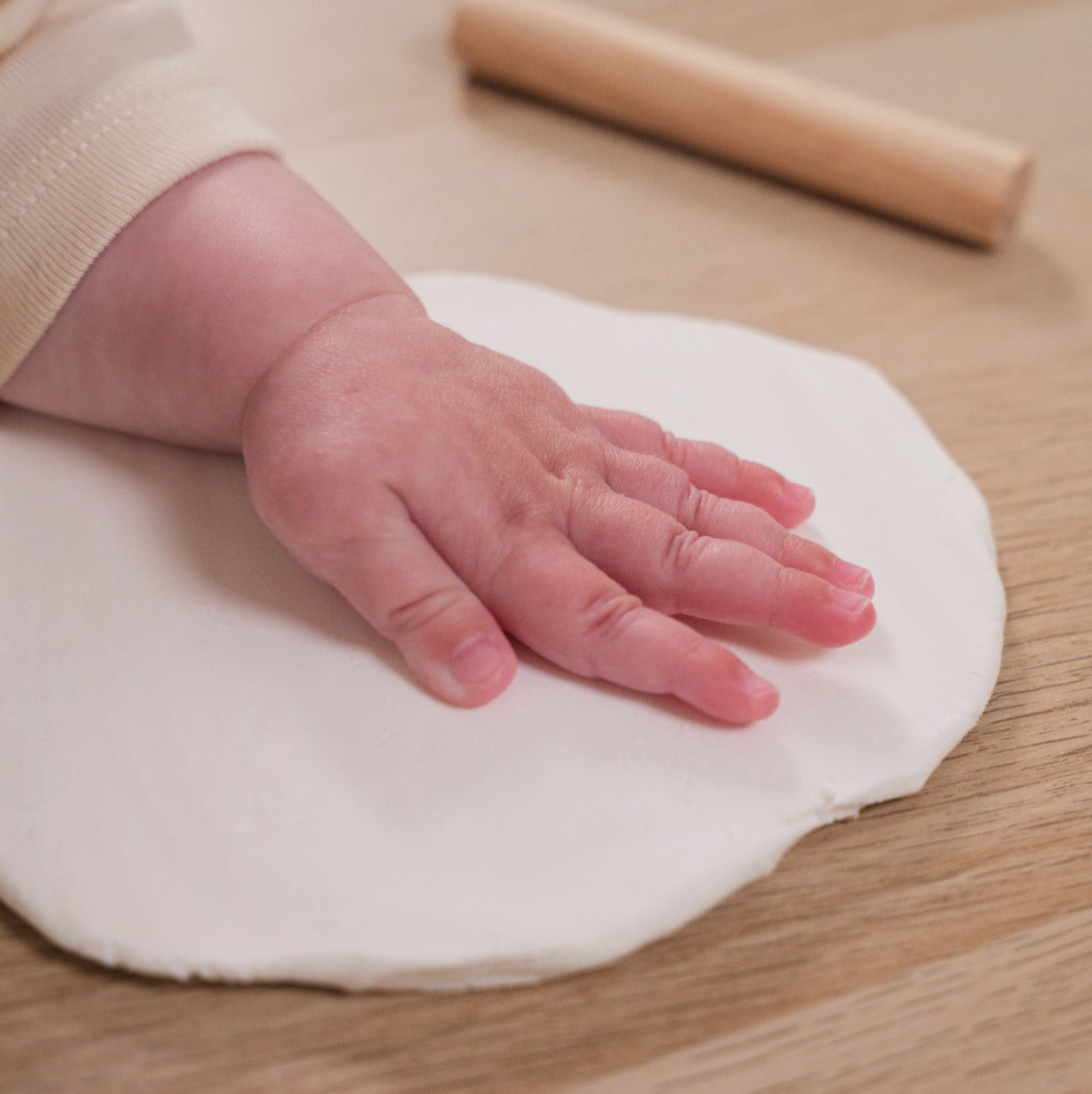 Baby imprinting hand on hypoallergic clay in wooden hanging