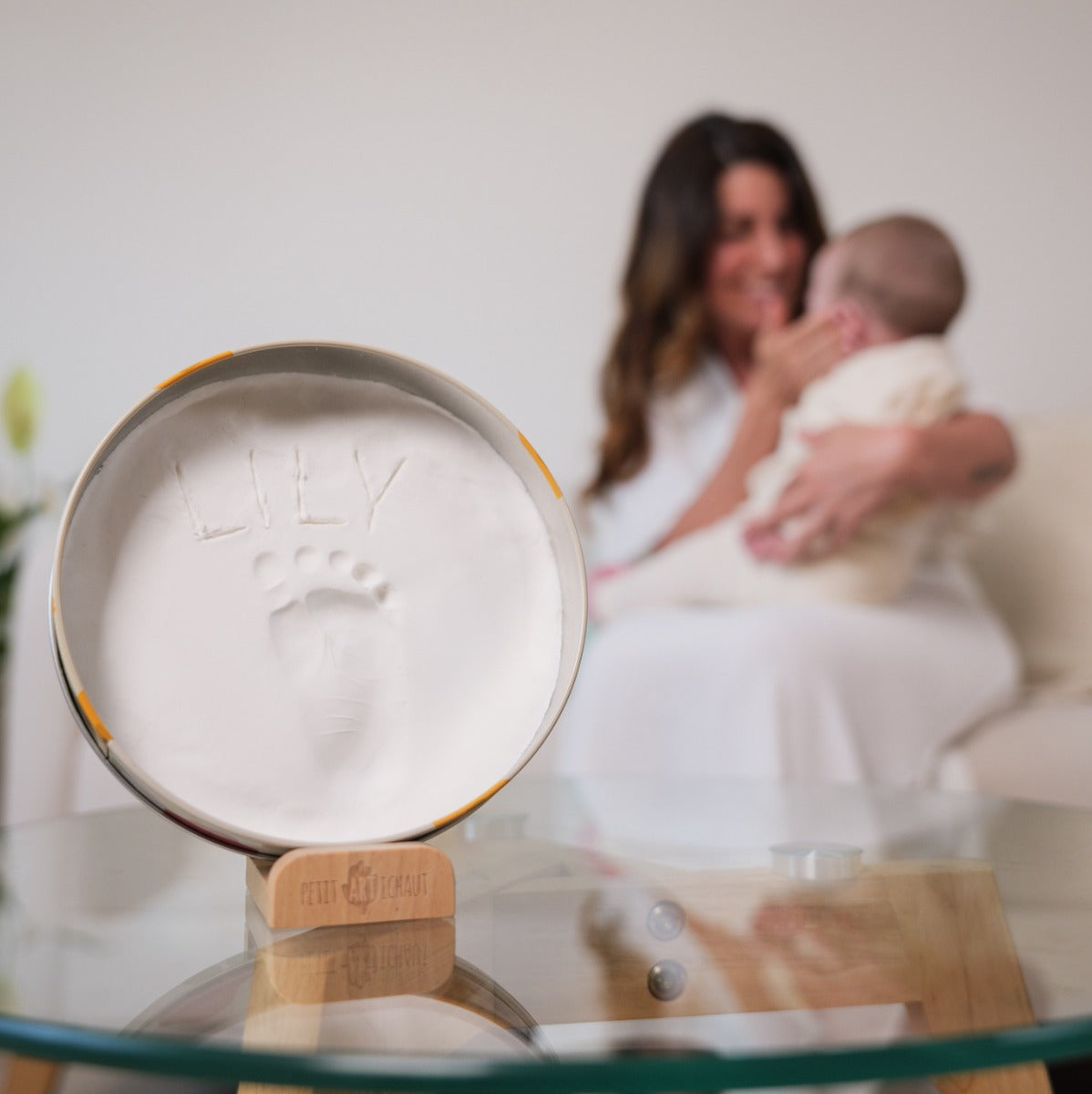 Petit Artichaut baby box round in little prairie print placed on a table with mother and baby in the background