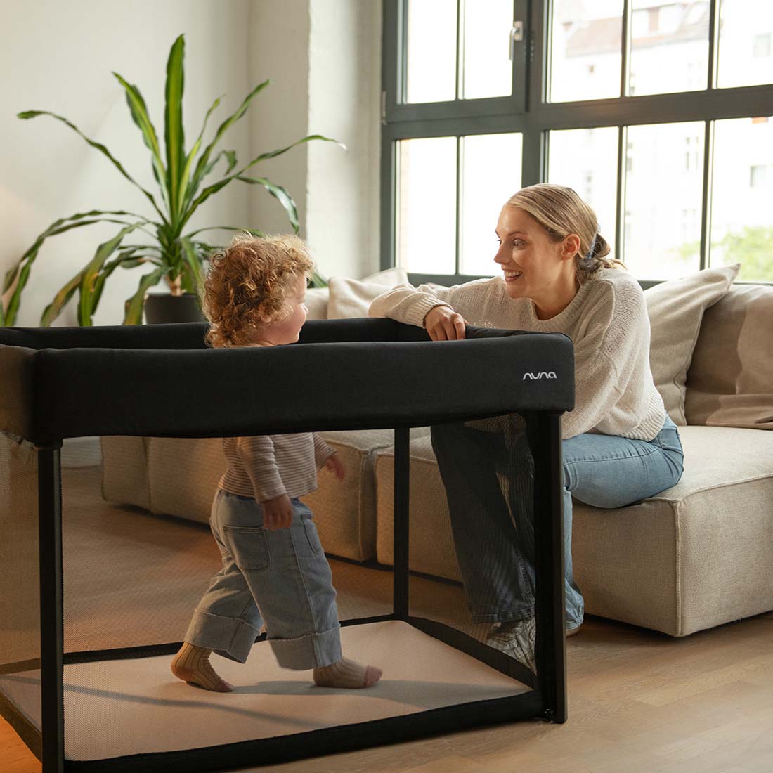 Baby playing in Nuna Paal bassinet and travel cot in caviar