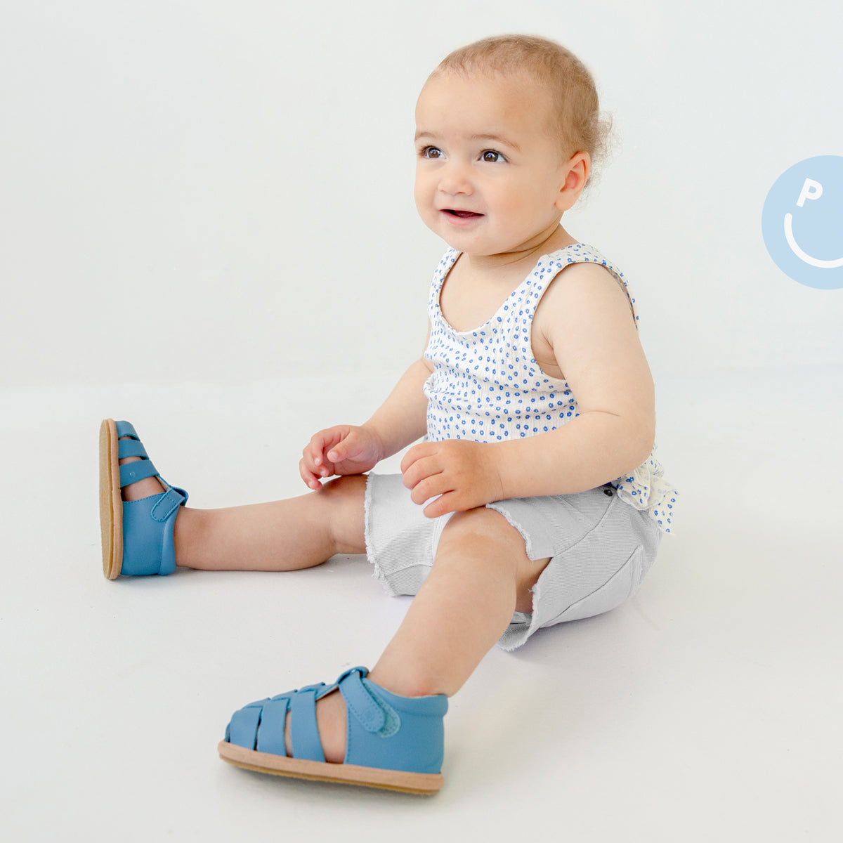 Baby wearing Pretty Brave Rio Baby Sandals in Playground Blue while sitting down