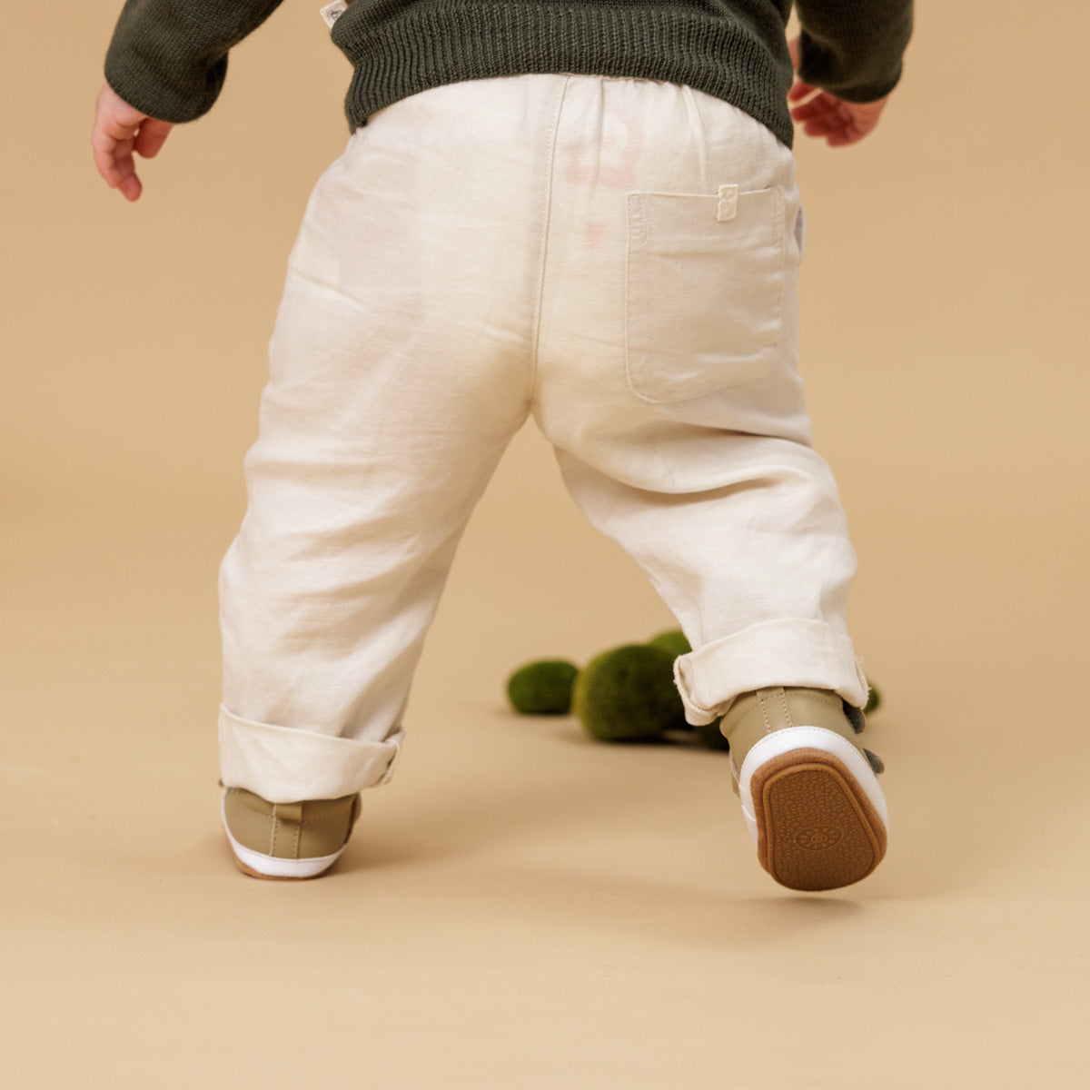 Baby wearing sage leather shoes with Velcro