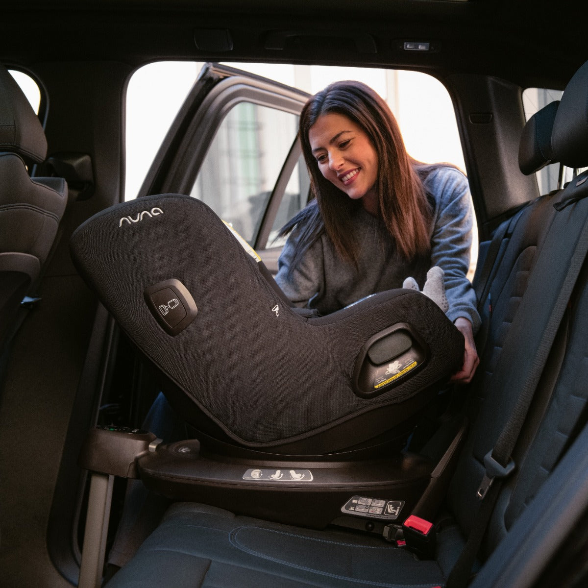Baby boy sitting in a Pruu car seat in car back seat rear facing
