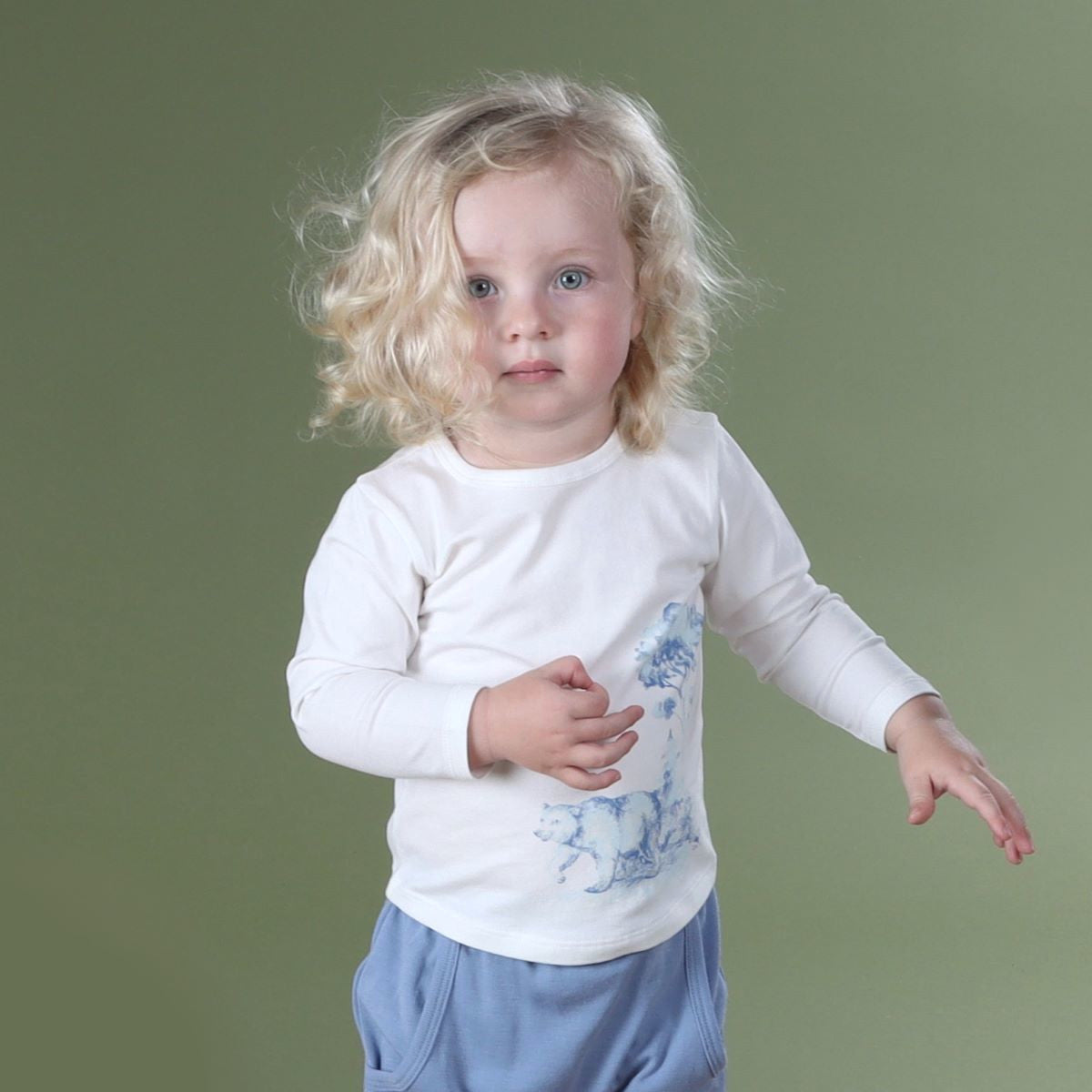 Baby boy standing wearing cotton long sleeve top with blue merino pant