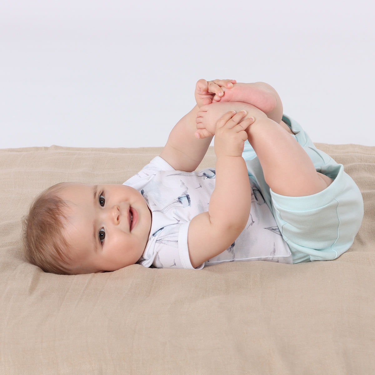 Baby sleeping wearing organic cotton bodysuit with boats print pairing it with blue shorts