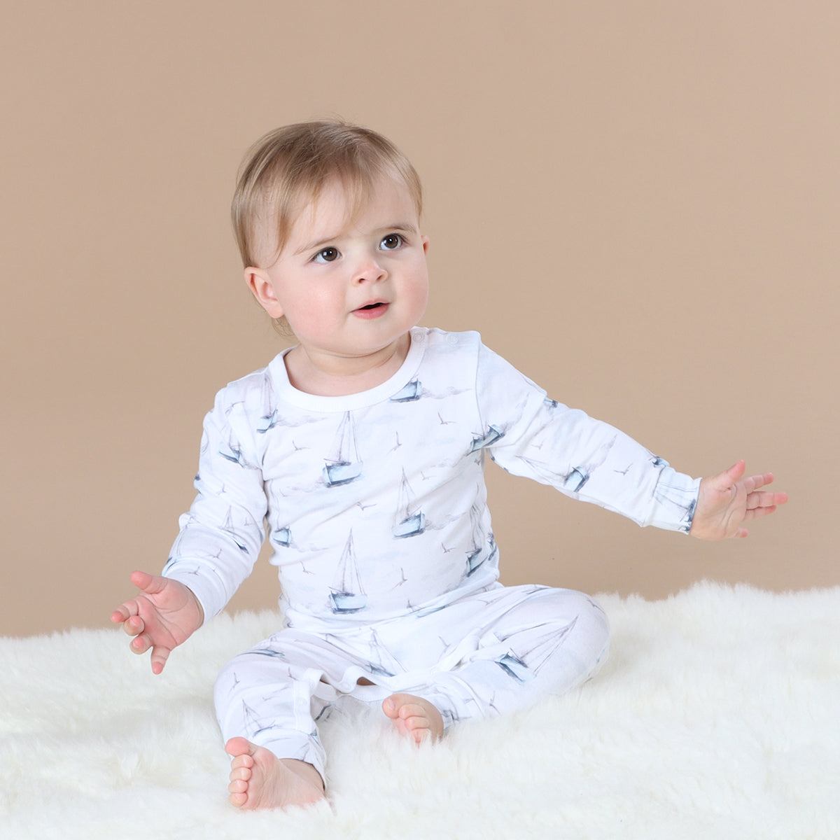 Baby wearing organic cotton one-piece with boats print
