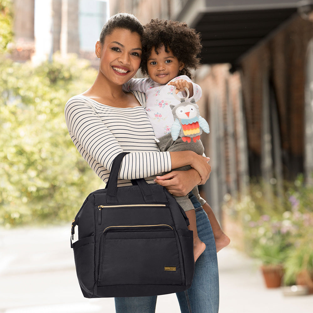 Mother holding baby and Main Frame Wide Open Backpack from Skip Hop