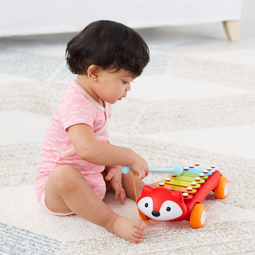 Baby girl playing with Explore & More Xylophone from Skip Hop  in red
