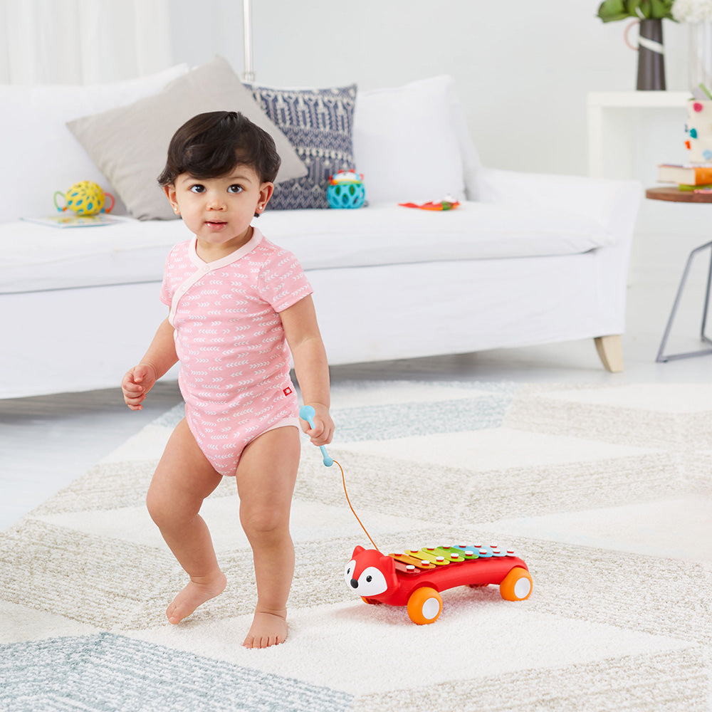 Baby girl pulling Explore & More Xylophone from Skip Hop  in red