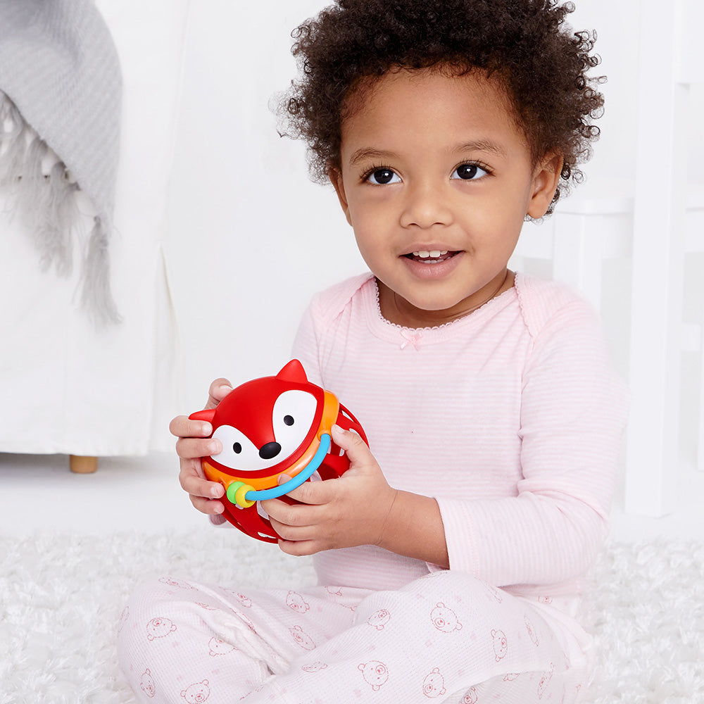 Baby girl playing with Explore & More Roll Around Rattle - Fox from Skip Hop