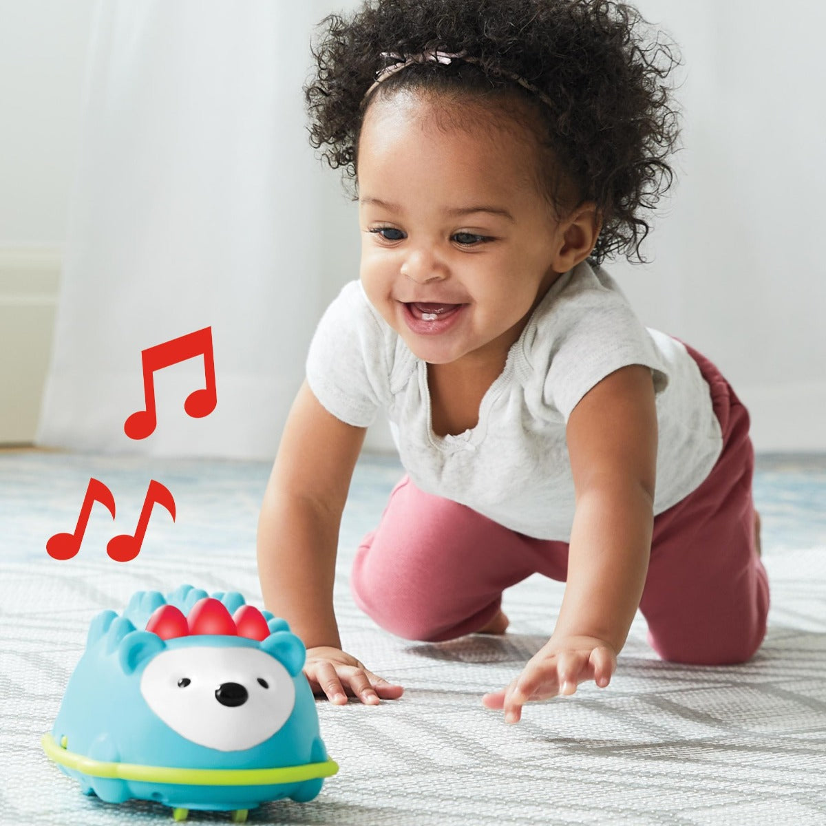 Little girl crawling toward Explore & More Hello Hedgehog Crawl Toy