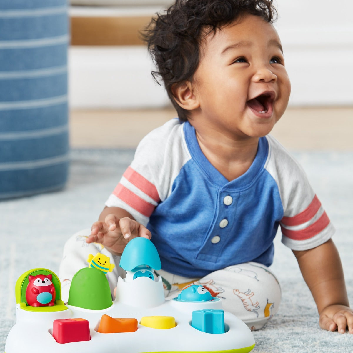 Happy boy playing with Explore & More Pop Up Toy from Skip Hop