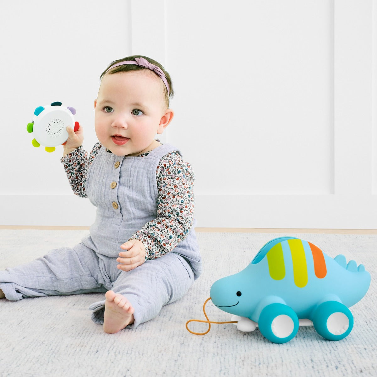 baby girl playing with Skip Hop Explore & More Dinosaur 3-In-1 Baby Musical Pull Toy rattle