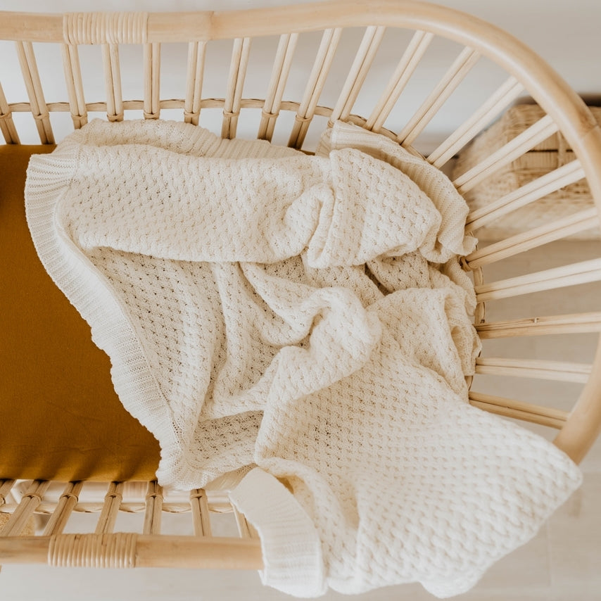 Snuggle Hunny Diamond Knit Blanket in cream in bed