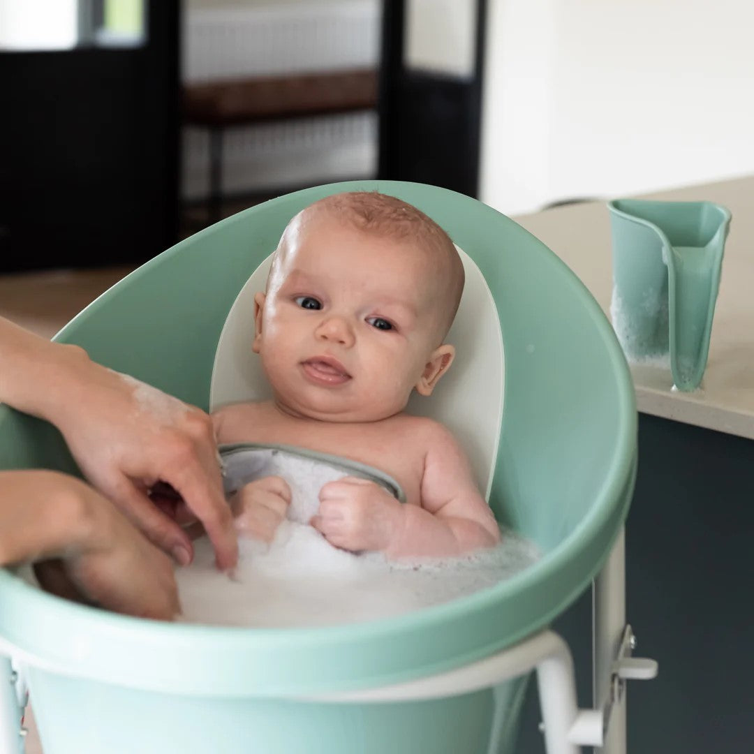 Mother bathing baby boy in a Shnuggle eucalyptus with washy bath jug