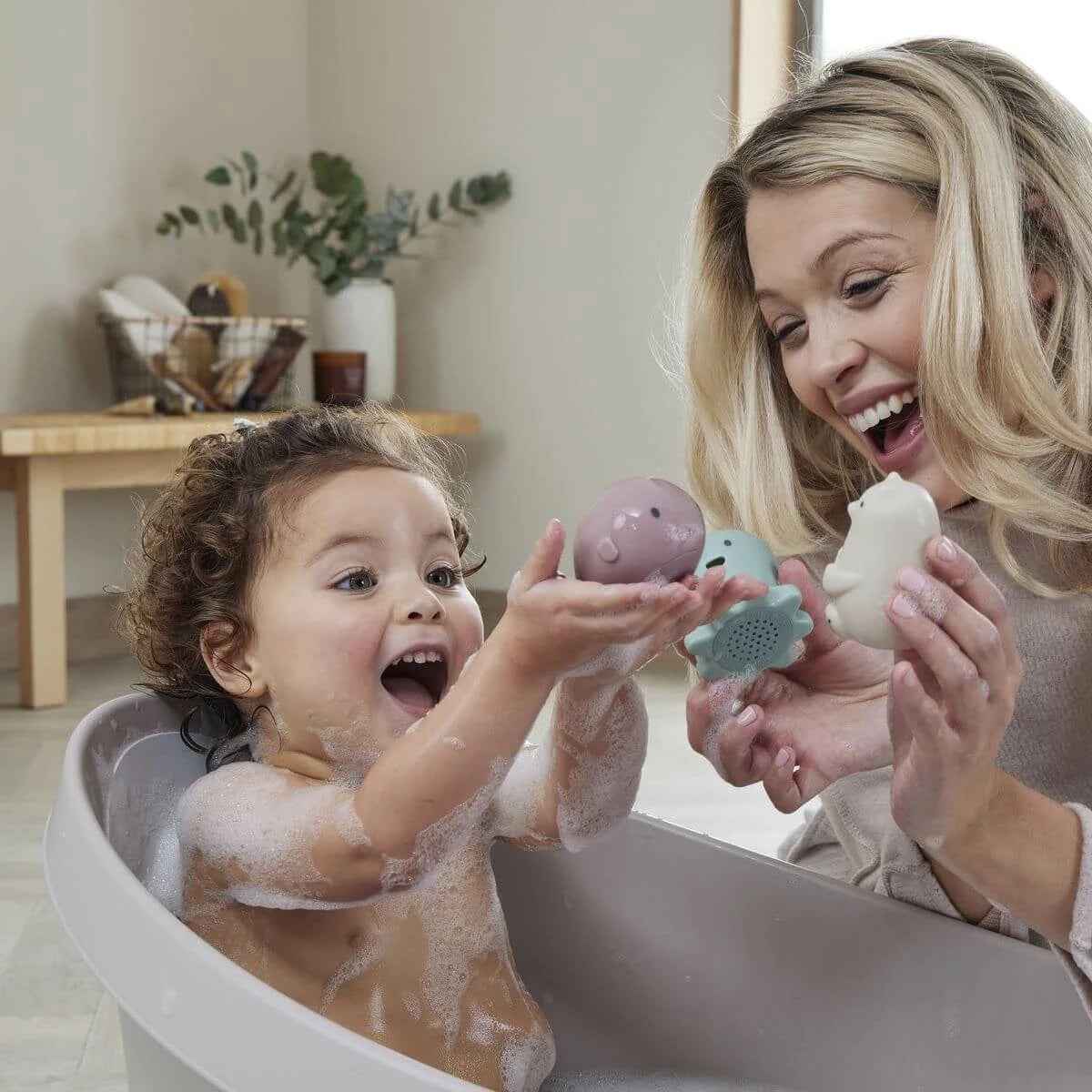 Baby boy playing with bath toys in Shnuggle Bath