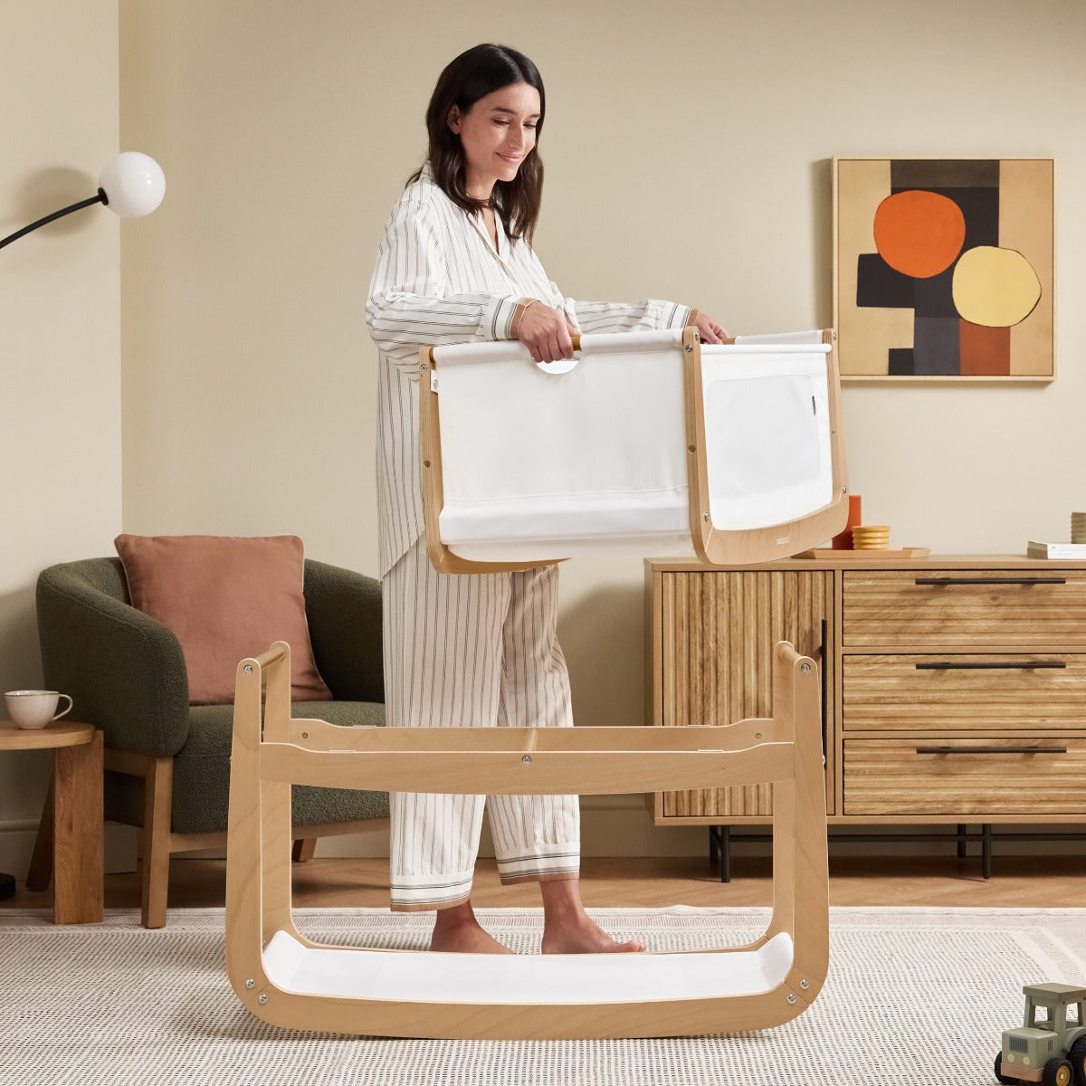 Mother holding swing of Snuzpod 5 Natural Wood Frame Bedside Baby Crib