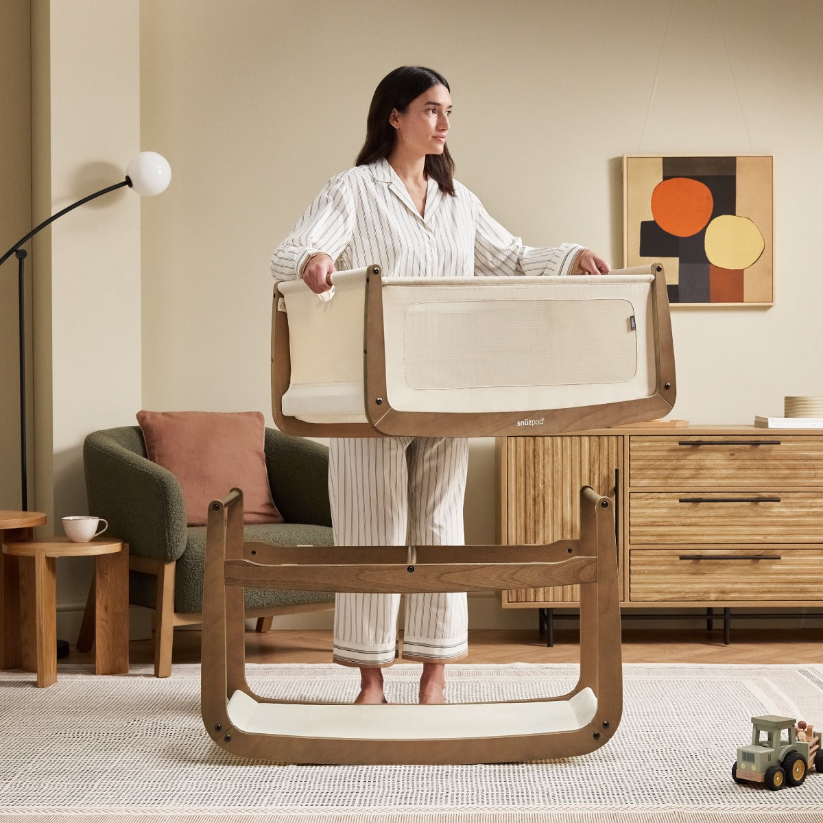 Mother pulling bassinet from Snuzpod 5 Walnut Wood Frame Bedside Baby Crib