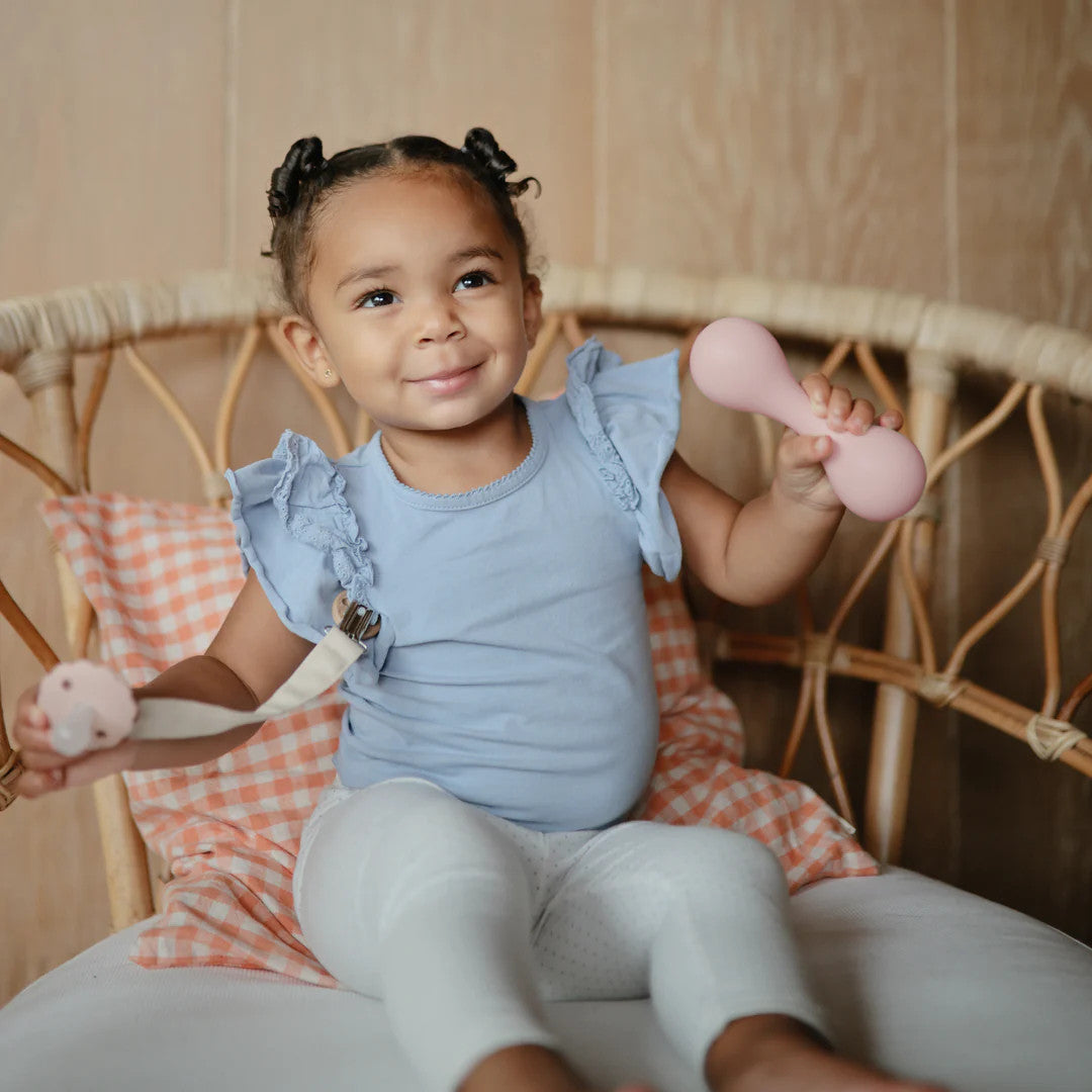 Mushie silicone baby rattle in blush with child