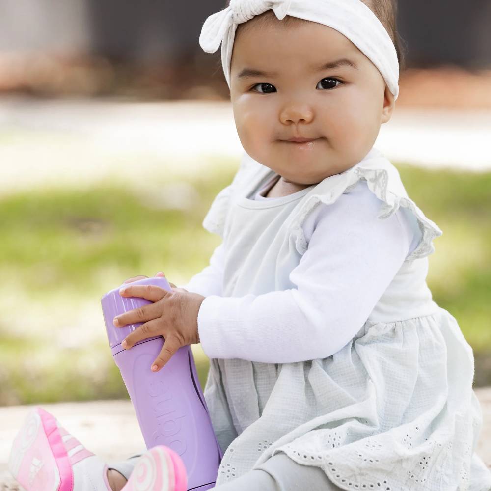 happy toddler holding Subo Food Bottle purple