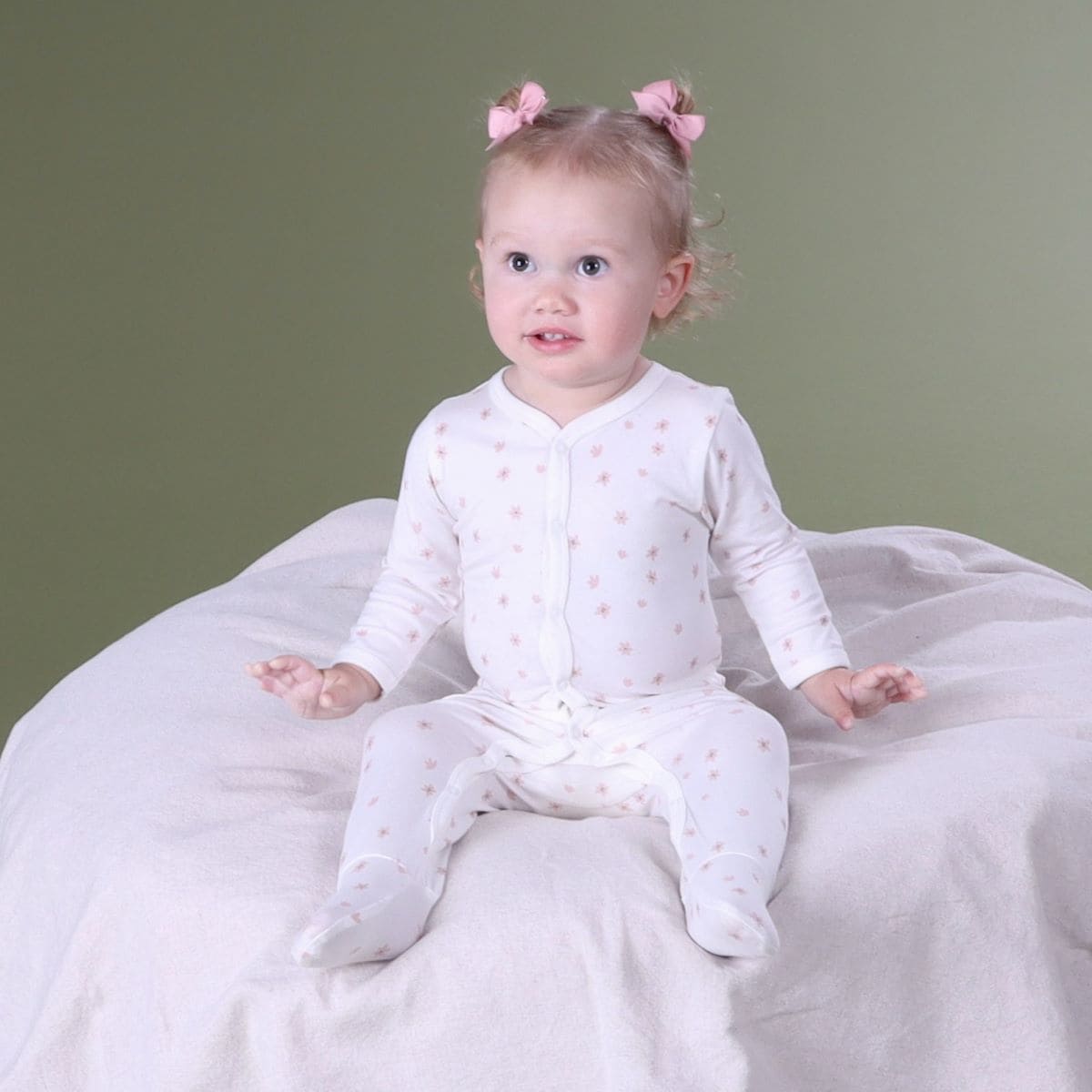 Baby girl sitting on a lounger wearing dainty floral baby grow