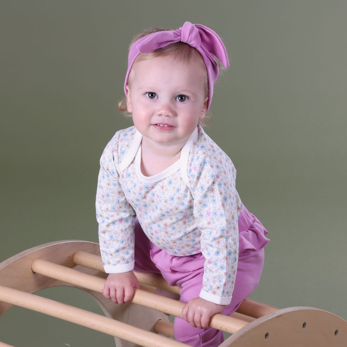 Baby girl wearing floral long sleeve body suit pairing it with headband and frill pant