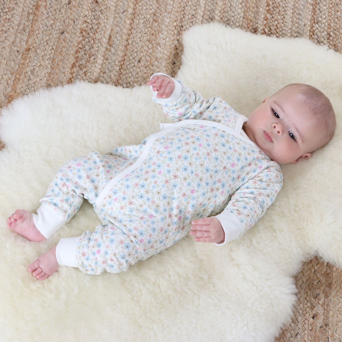 Baby girl sleeping on rug wearing cotton floral tie baby grow