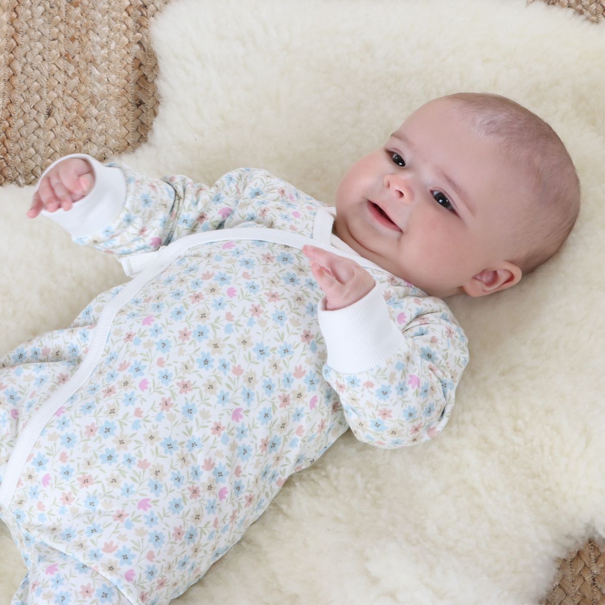 Baby girl sleeping on rug wearing cotton floral tie baby grow