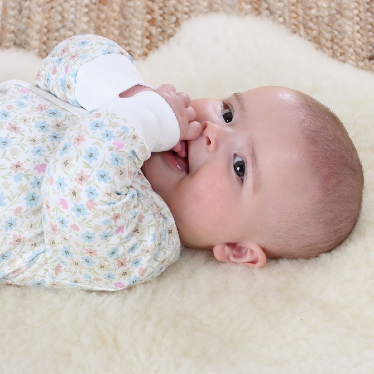 Baby girl sleeping on rug wearing cotton floral tie baby grow