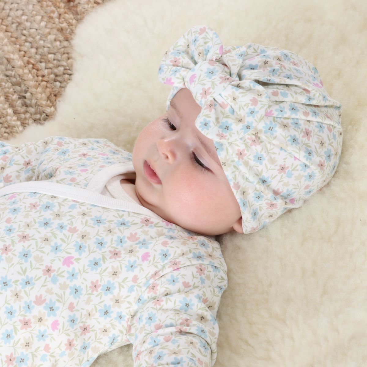 Baby girl wearing Floral Cotton Bow Beanie  and lying on a rug