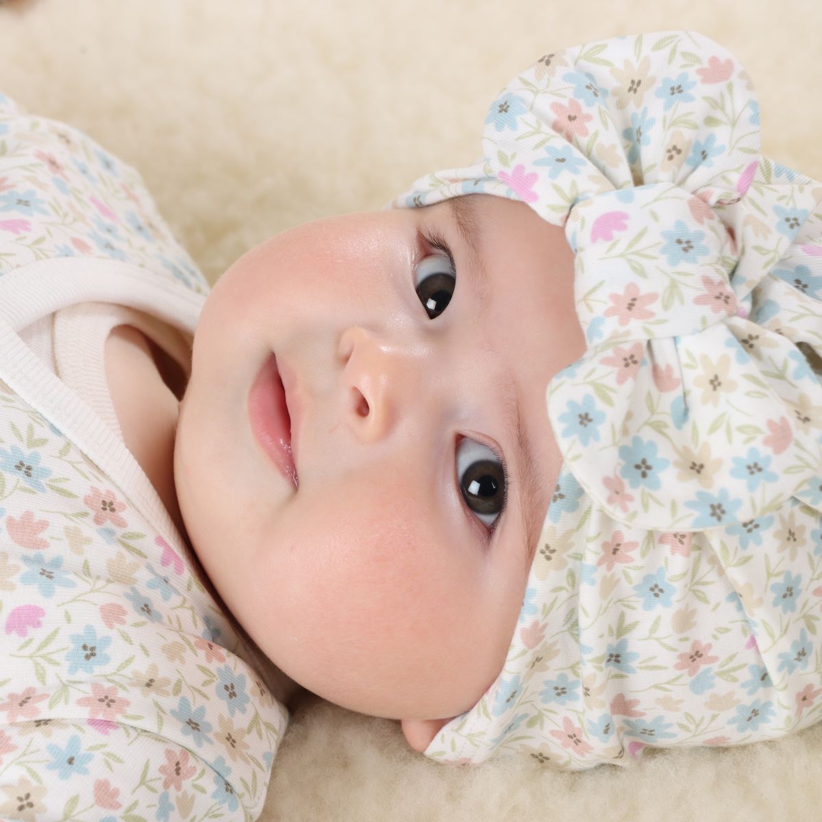 Baby girl wearing Floral Cotton Bow Beanie  and lying on a rug