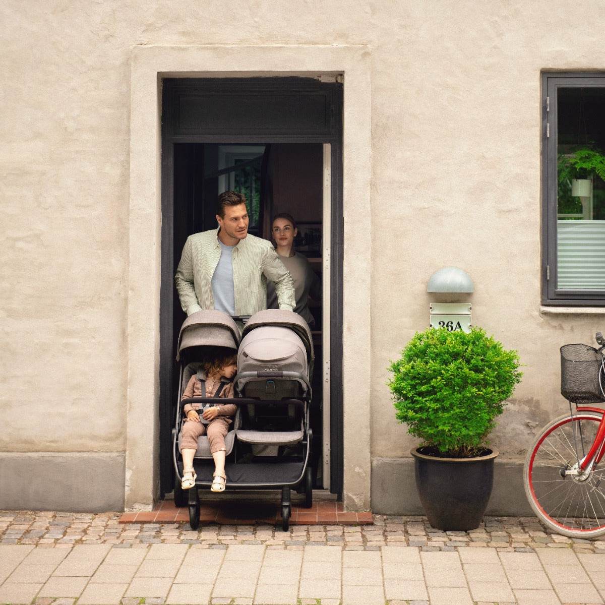 Father pushing Trvl Dbl pram through doorway