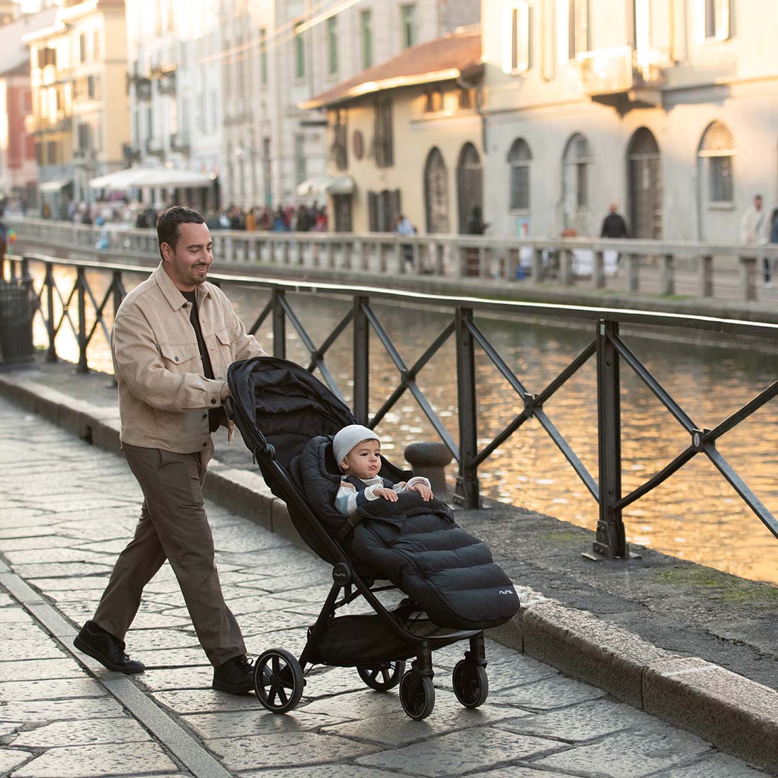 Father on road with kid in a stroller with Nuna winter set footmuff