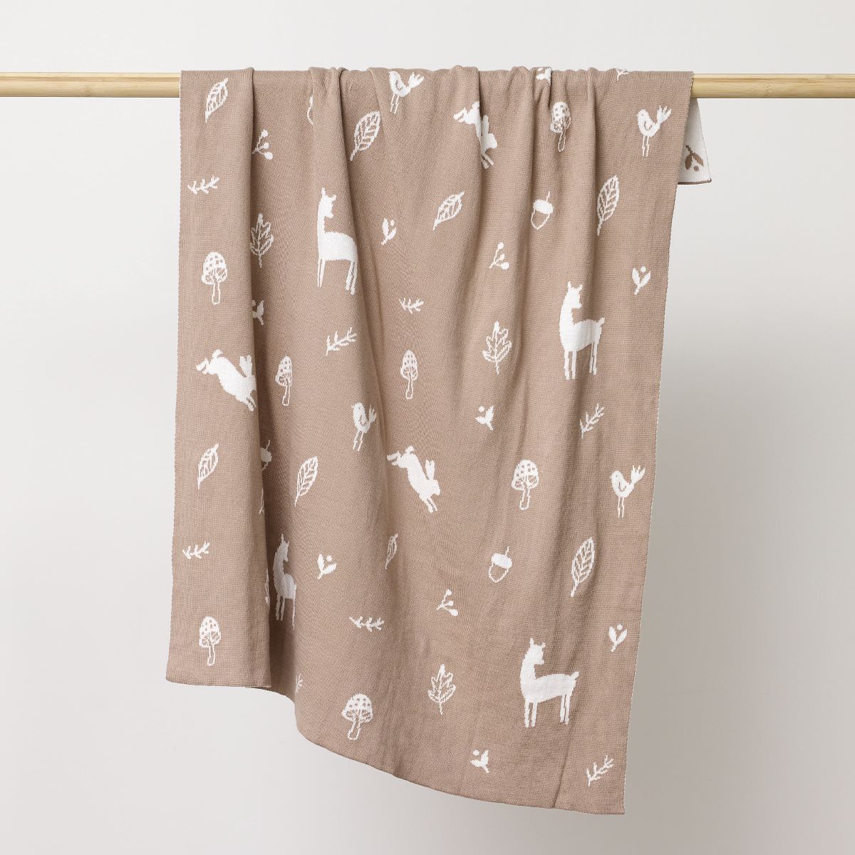Mushroom coloured blanket with sparrows, deers, flowers and leavers printed in white hanging on the wooden rod to display.:image,small_image,thumbnail,swatch_image