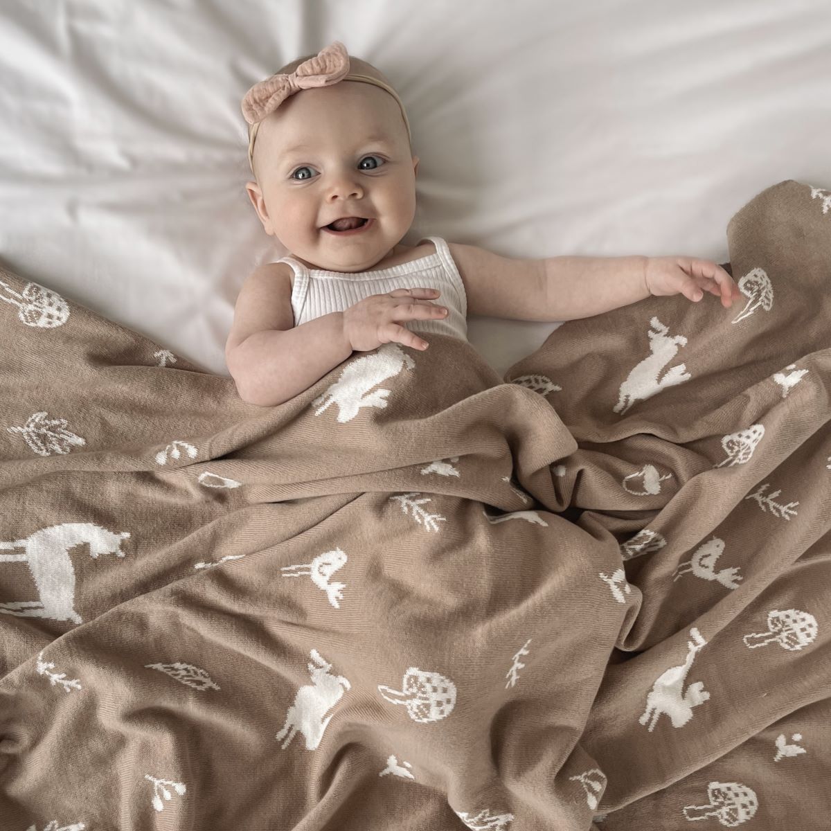 Happy baby sleeping with mushroom coloured blanket with sparrows, deers, flowers and leavers printed.