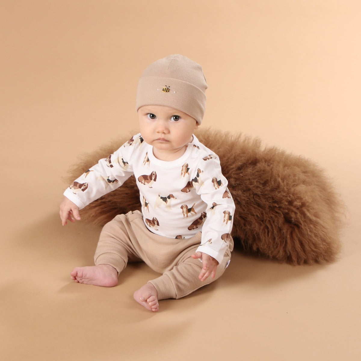 Baby boy wearing cotton bodysuit in dog print pairing it with merino pant and beanie