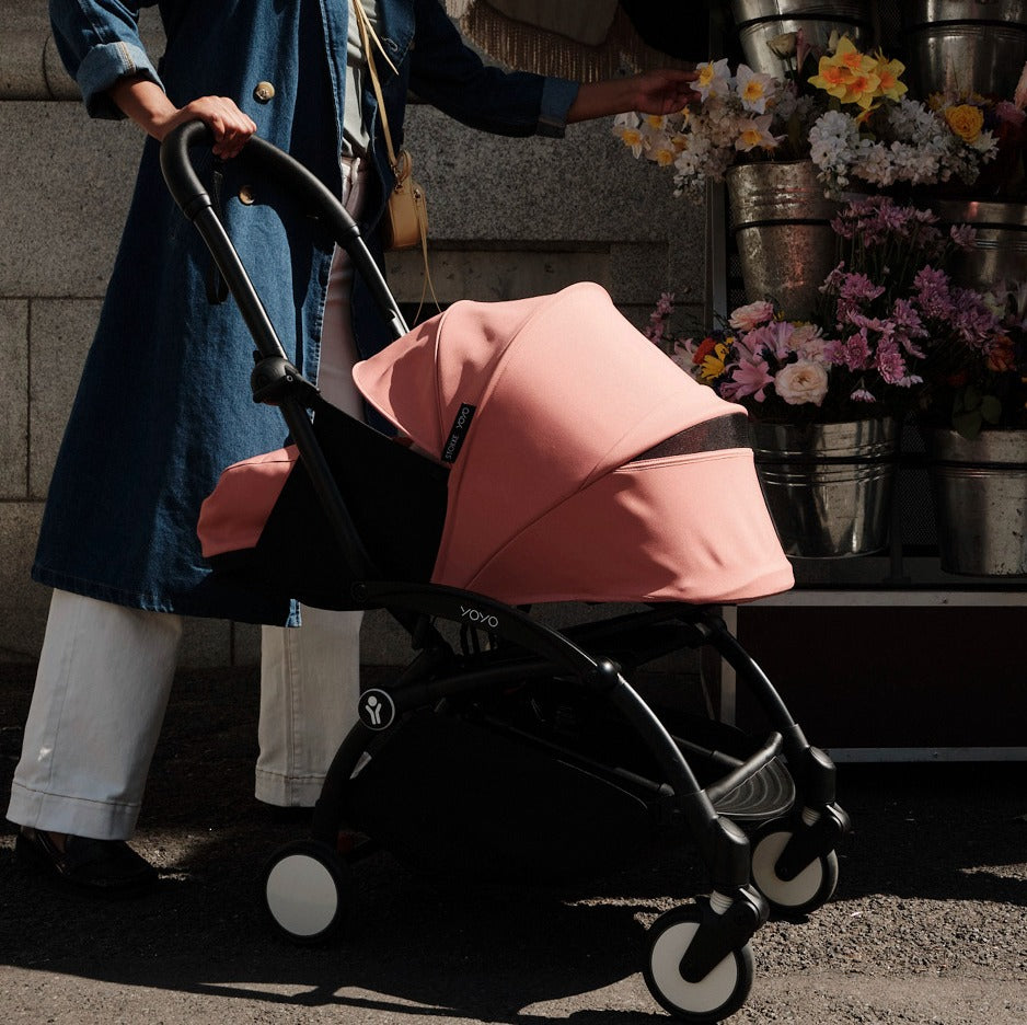 Mother buying flowers on road with baby sleeping in YOYO3 pram 
