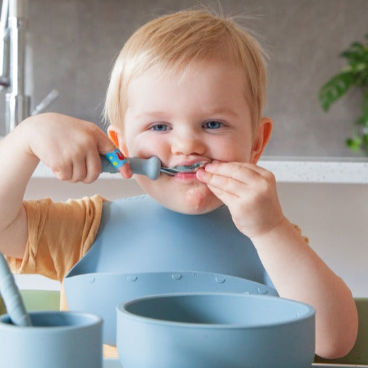 Baby eating with Zazi spoon wearing bib