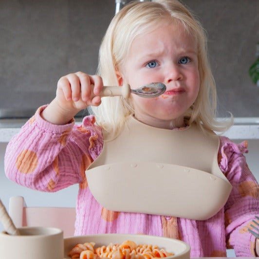 Baby eating with Zazi spoon wearing bib